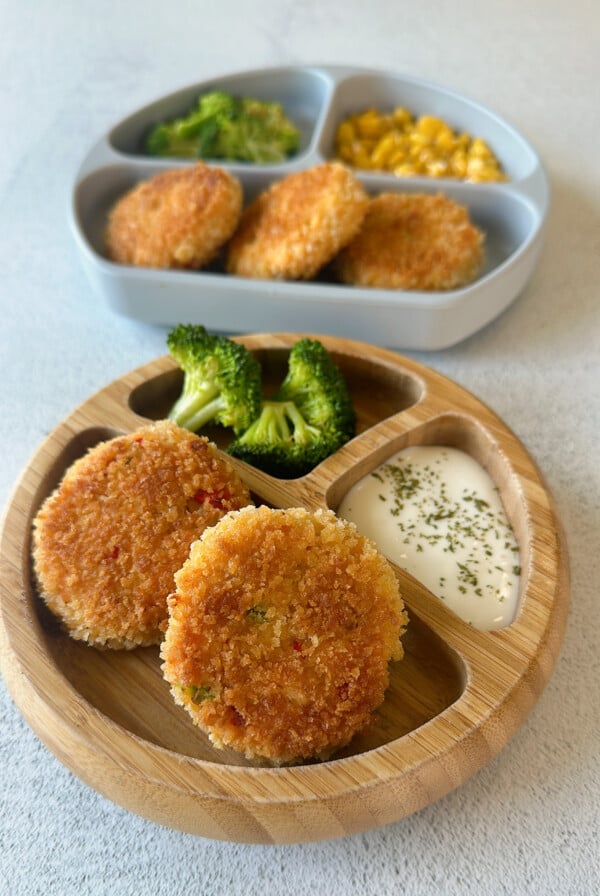 Salmon cakes served with broccoli, dip, and corn.