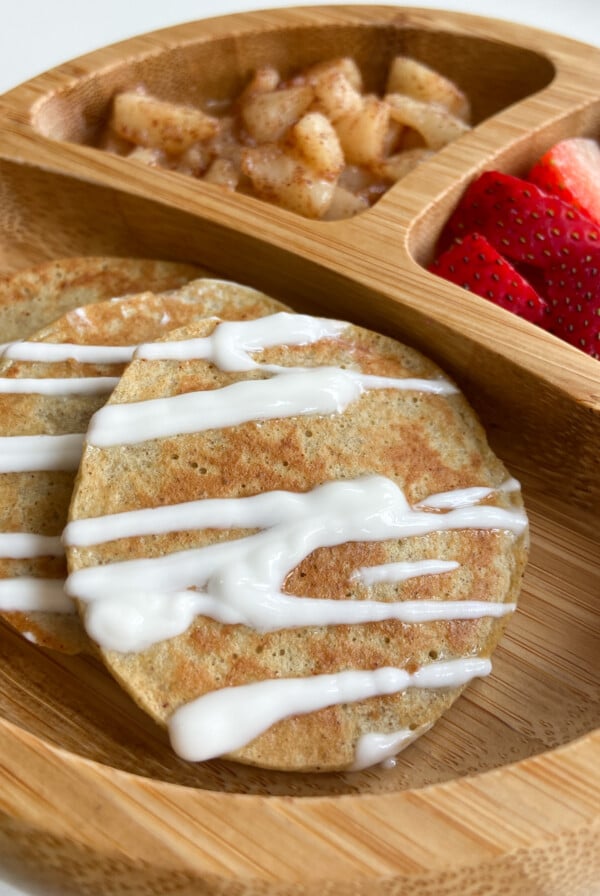 Pear pancakes served with cinnamon pears and strawberries. Drizzled with yogurt.