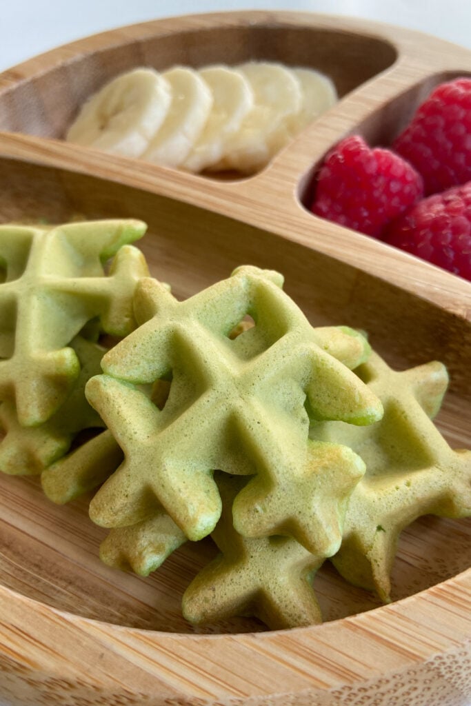 Spinach banana waffles served with sliced bananas and raspberries