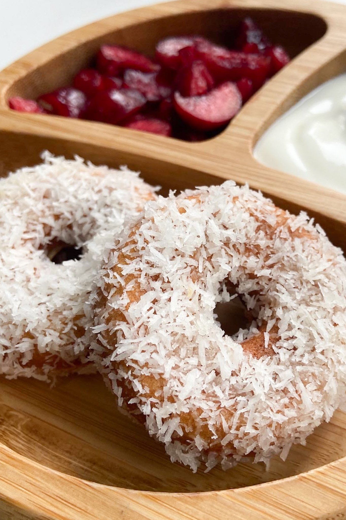Coconut donuts served with sliced cherries and yogurt