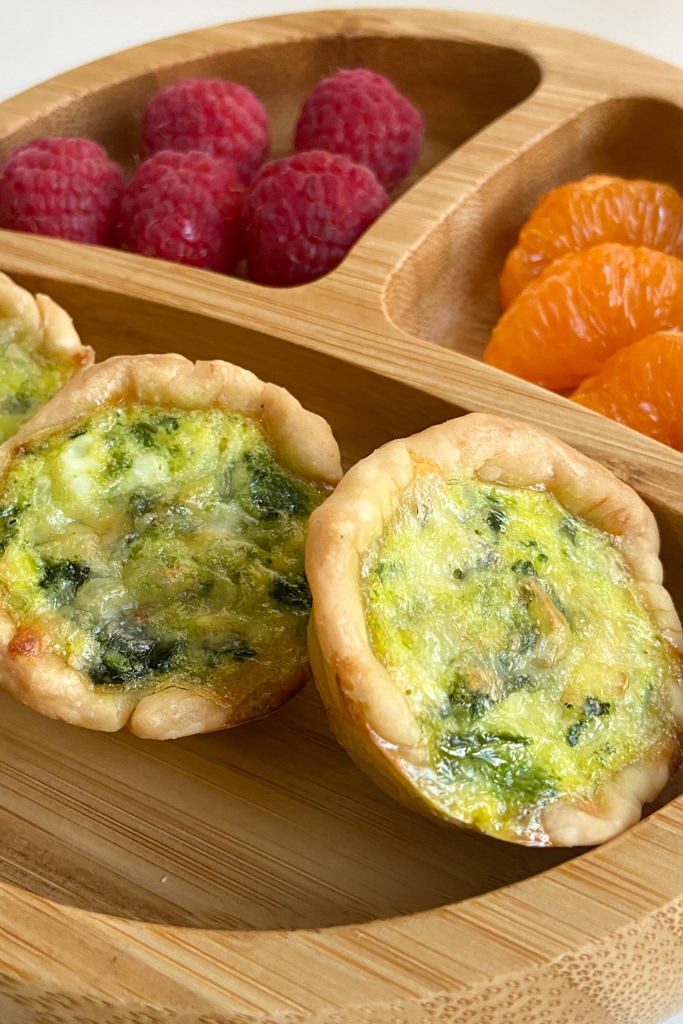 Mini spinach quiche served with raspberries and mandarins