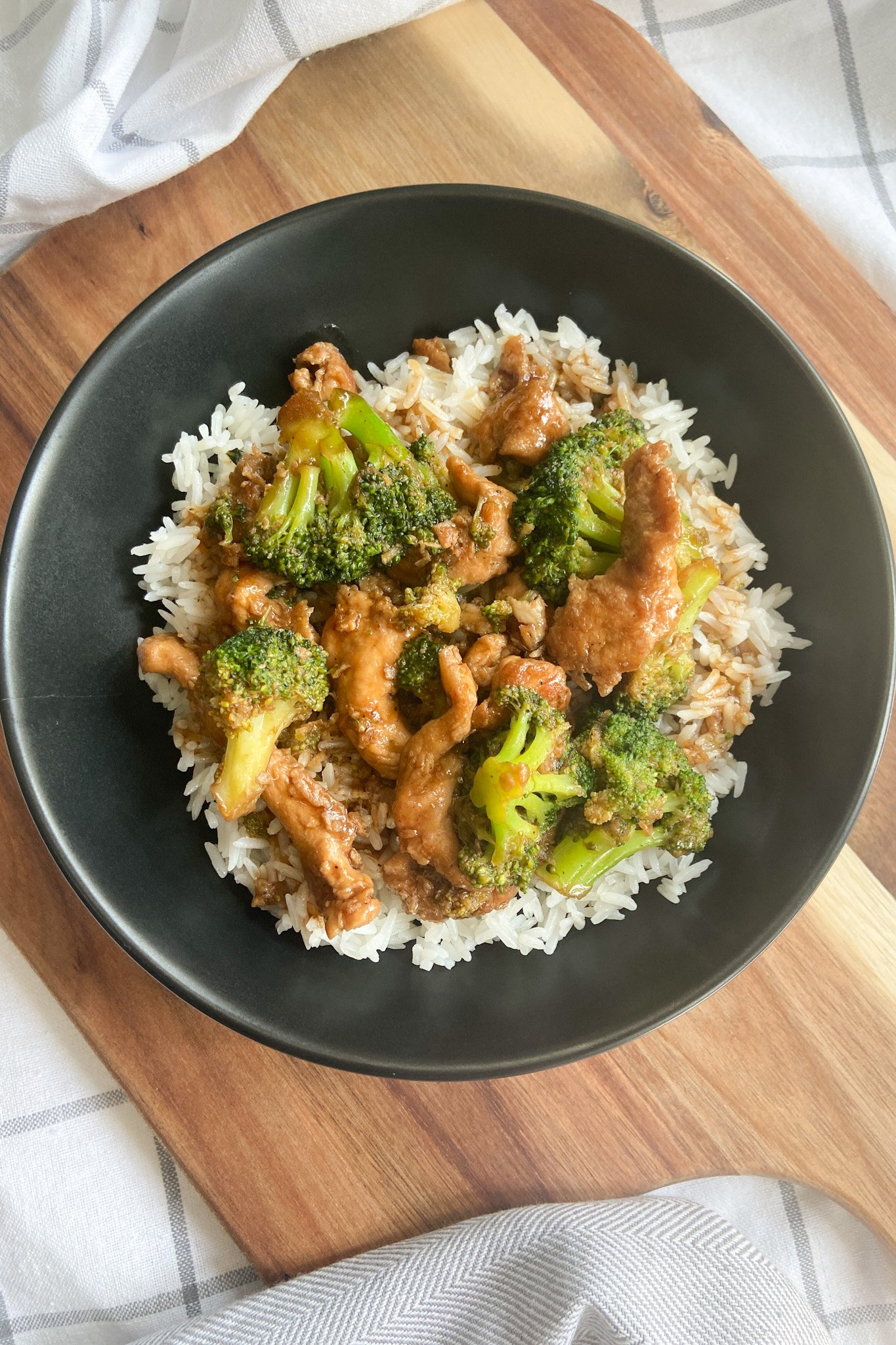Chicken and broccoli stir-fry served in a black bowl