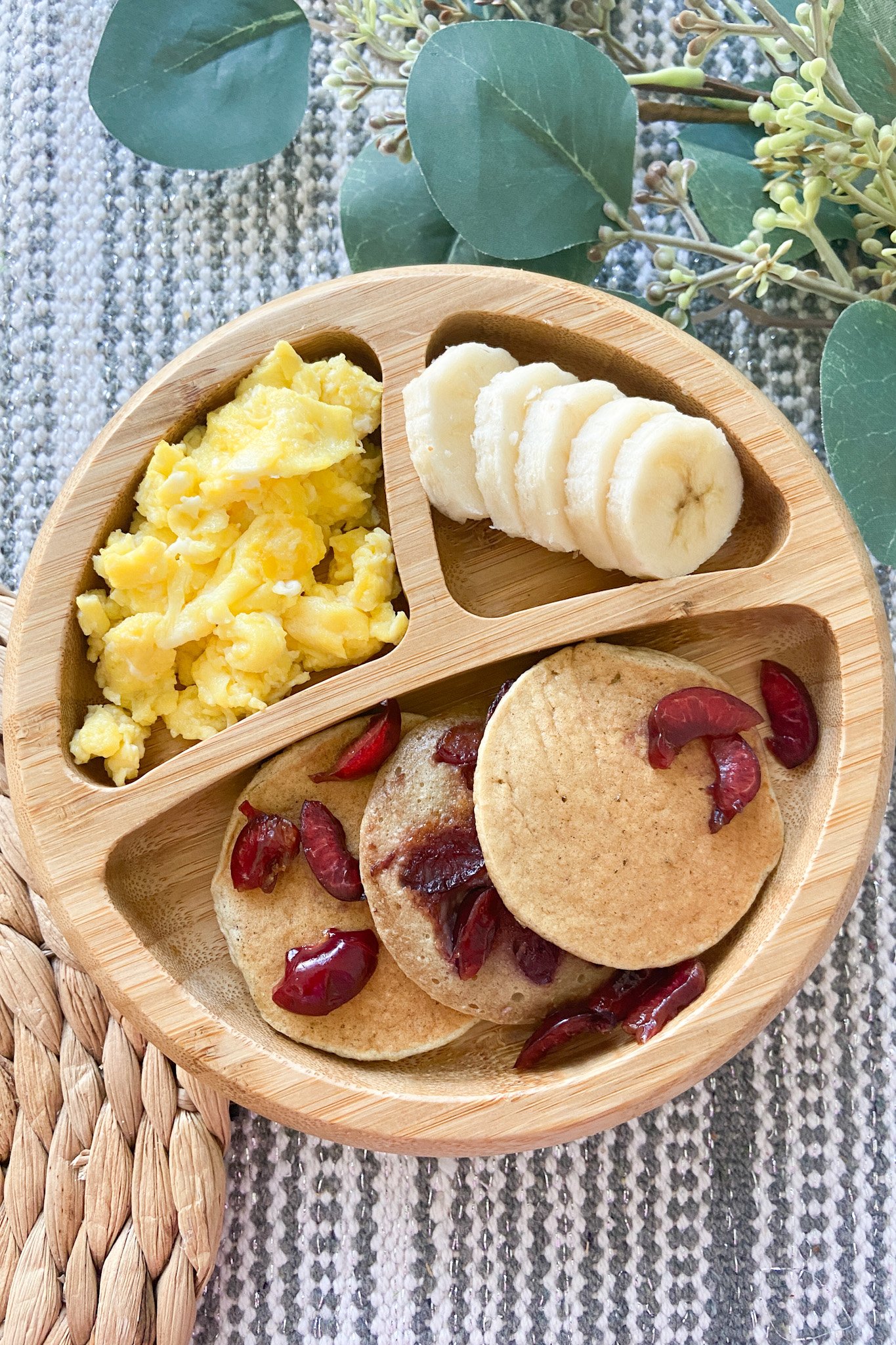 Oatmeal banana pancakes served with cherries, scrambled eggs and sliced bananas.