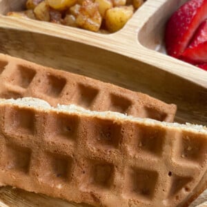 Cinnamon apple waffles served with cinnamon apples and sliced strawberries