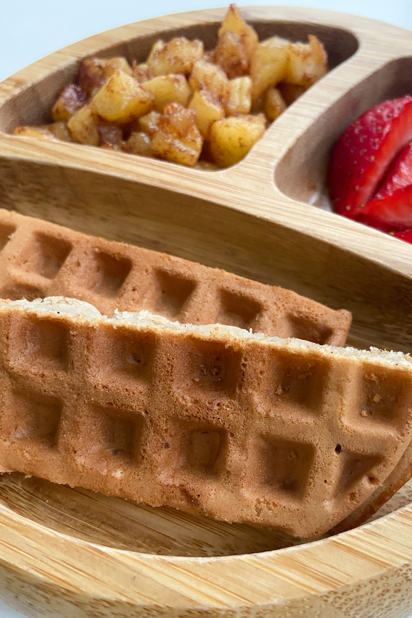 Cinnamon apple waffles served with cinnamon apples and sliced strawberries