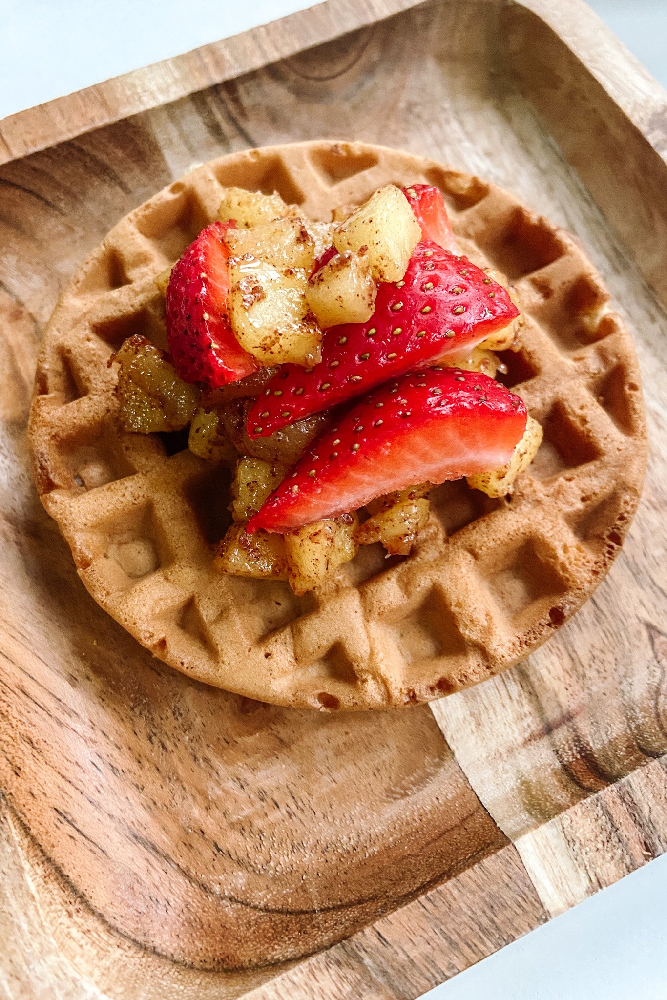 Cinnamon apple waffles topped with cinnamon apples and sliced strawberries