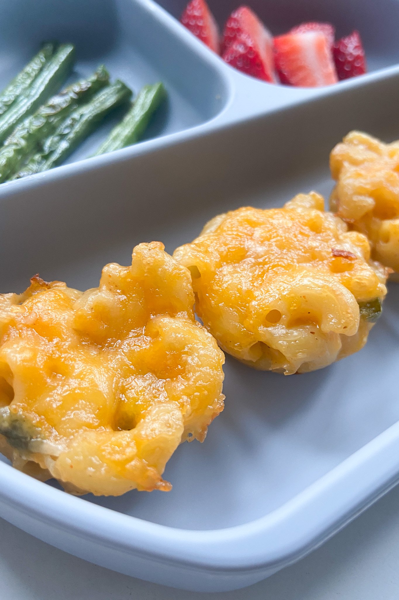 Mac and cheese bites served with green beans and strawberries