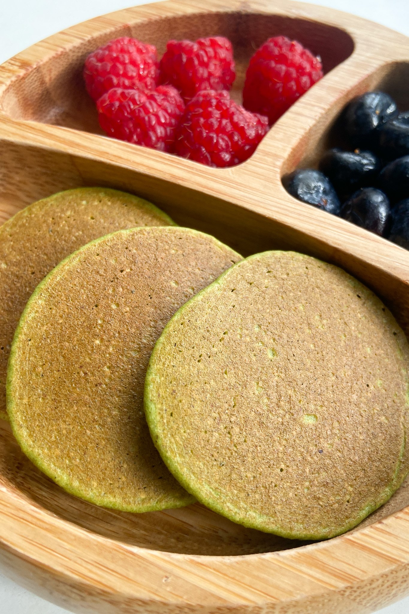 Spinach banana pancakes served with raspberries and blueberries