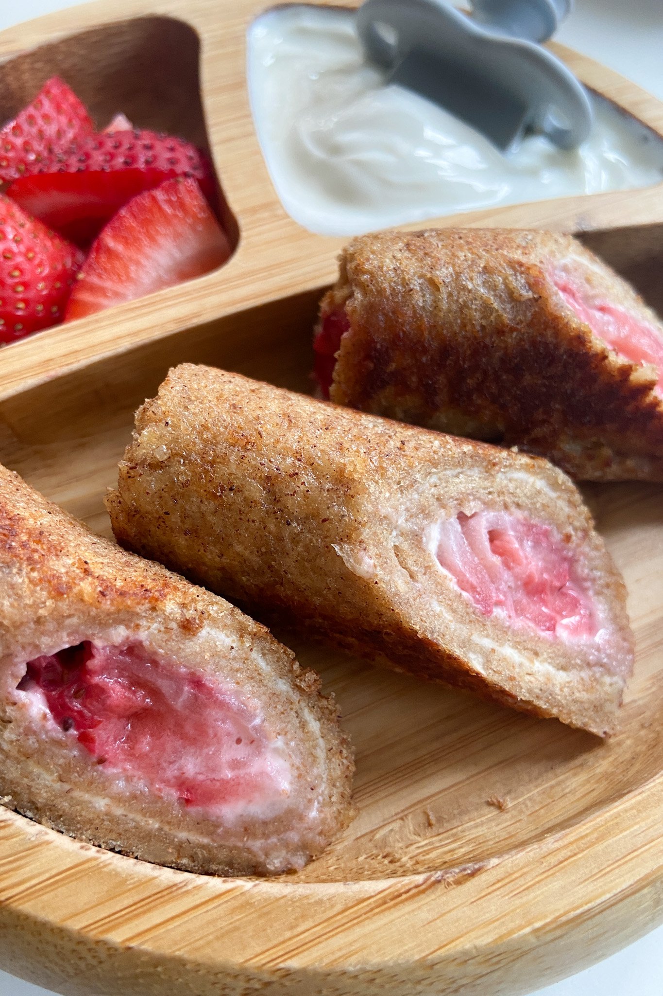 Strawberry cheesecake rollups served with sliced strawberries and yogurt