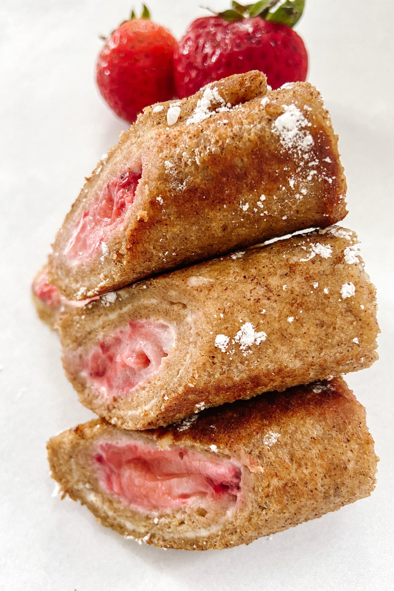 Strawberry cheesecake rollups served with strawberries and lightly dusted with powdered sugar