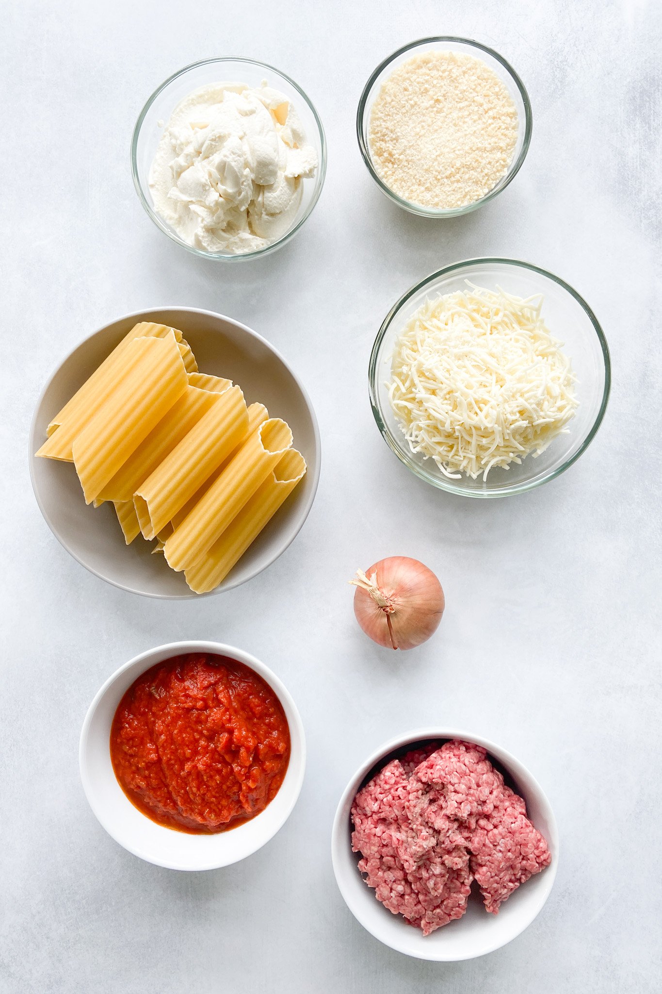 Ingredients to make cheesy beef manicotti. See recipe card for detailed ingredient quantities.