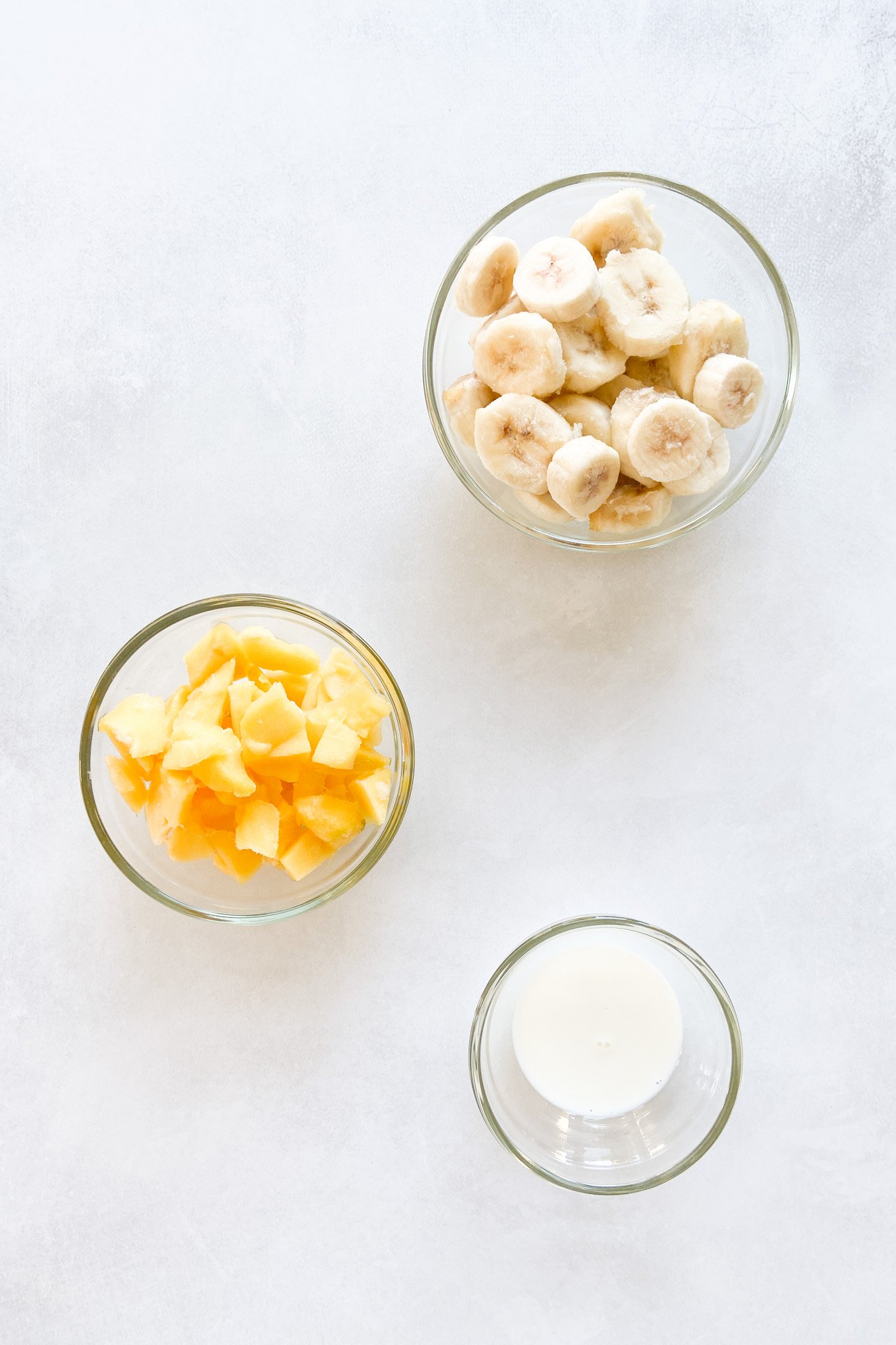 Ingredients to make mango banana nice cream. See recipe card for detailed ingredient quantities.