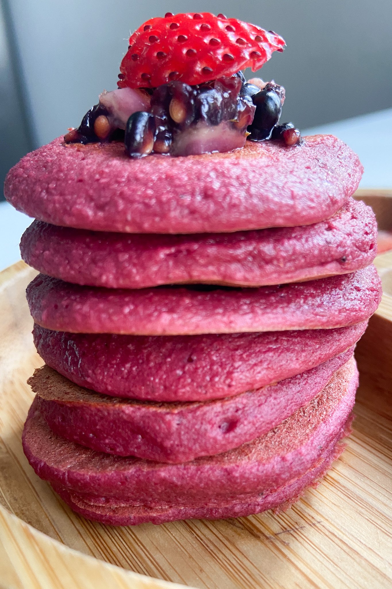 Beet banana pancakes topped with crushed blackberries and sliced strawberries