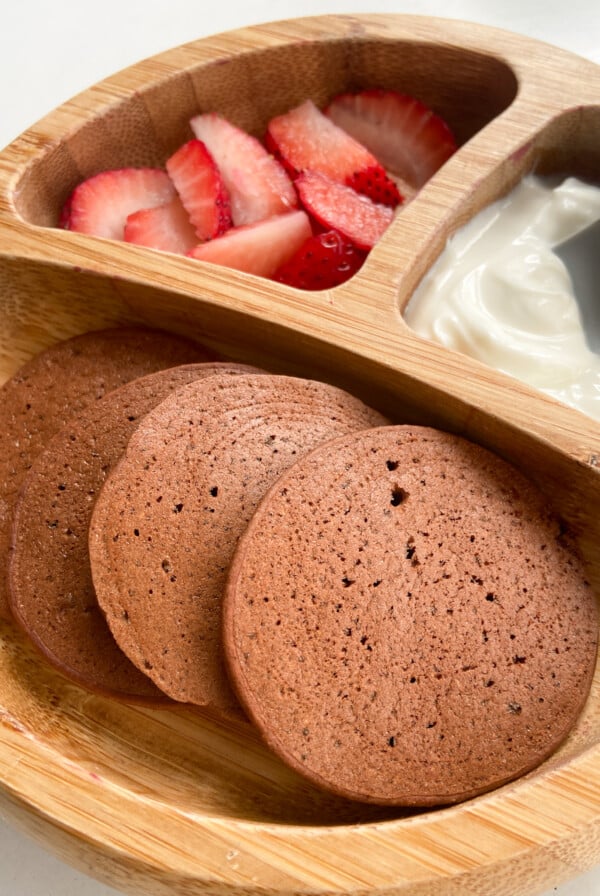 Chocolate banana pancakes served with sliced strawberries and yogurt