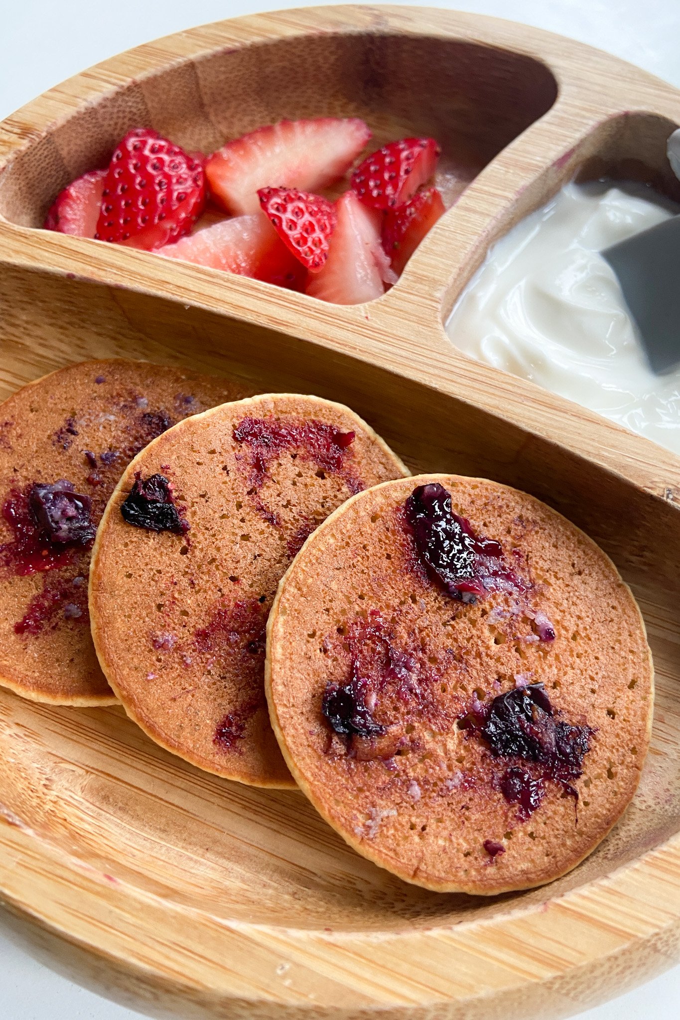 Blueberry oat pancakes served with sliced strawberries and yogurt