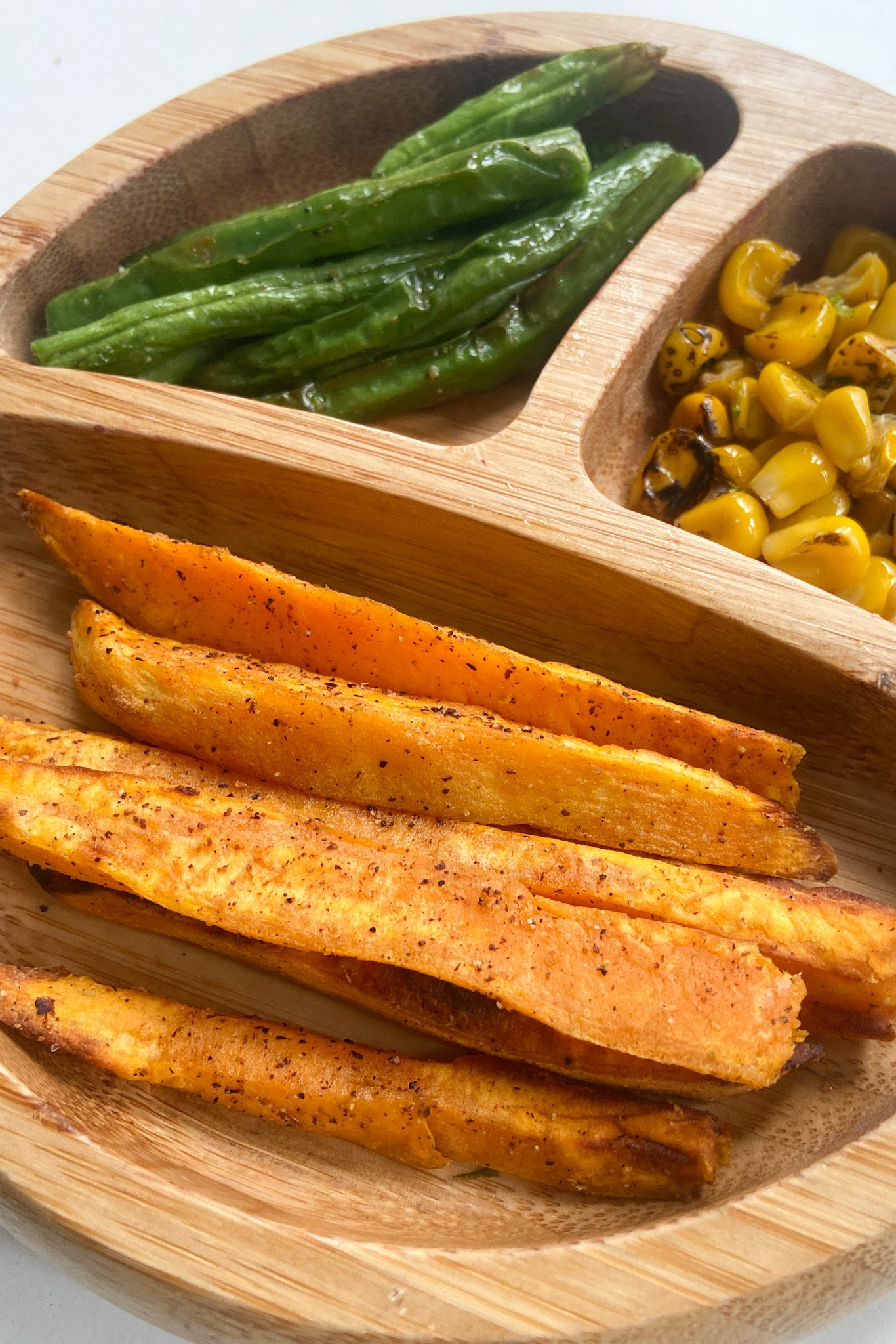 Air fryer sweet potatoes served with green beans and roasted corn