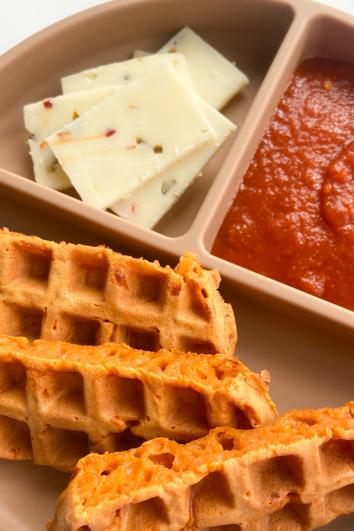 Pizza waffles served with sliced cheese and marinara sauce