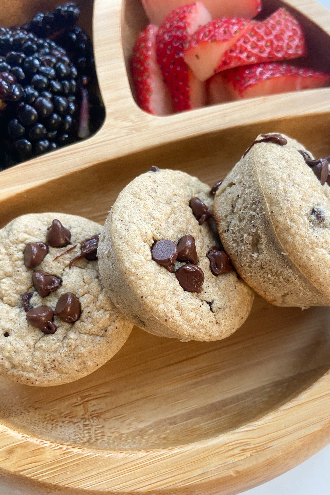 Chocolate chip oat muffins served with a side of quartered strawberries and blackberries