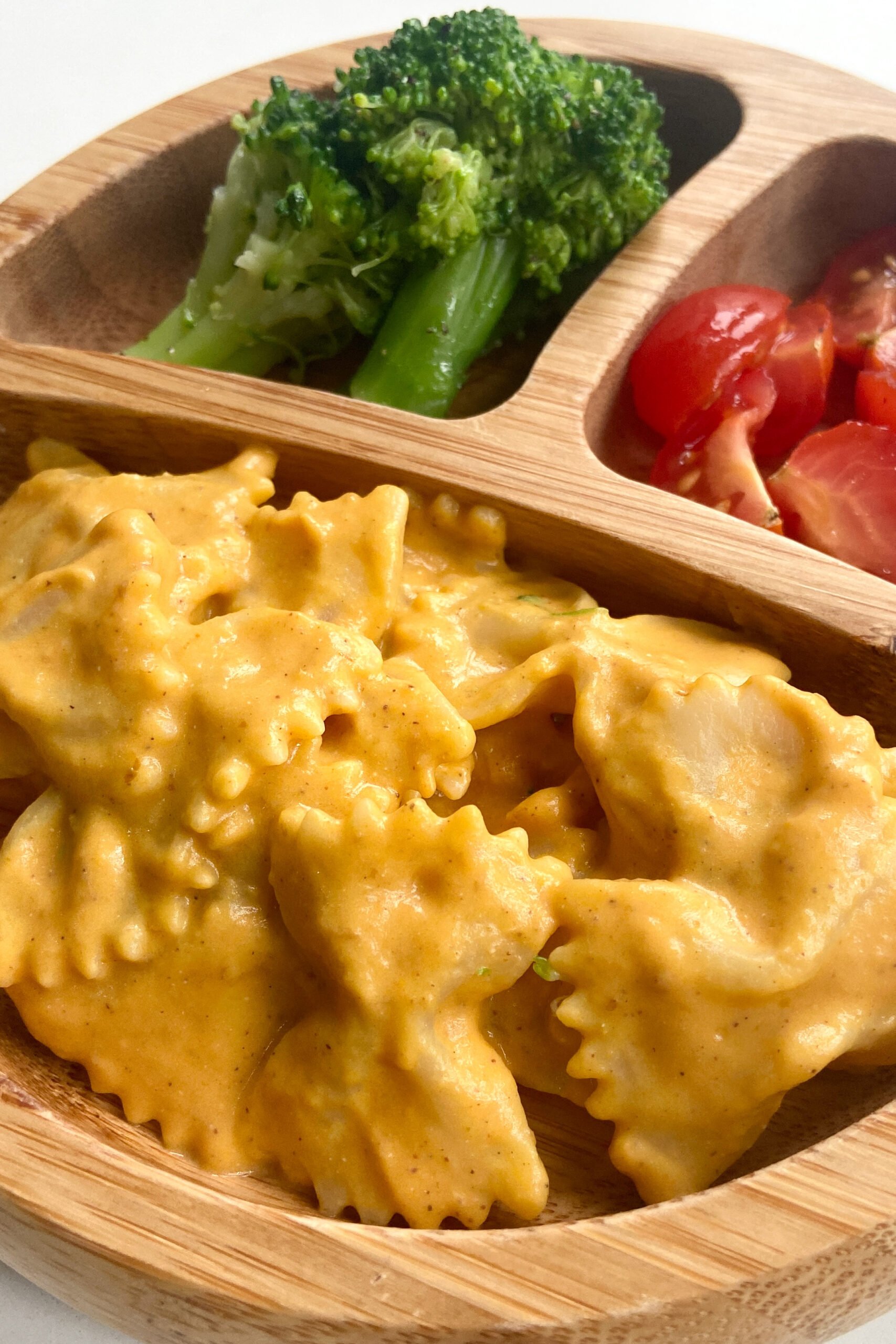 Creamy pumpkin pasta served with broccoli and quartered tomatoes