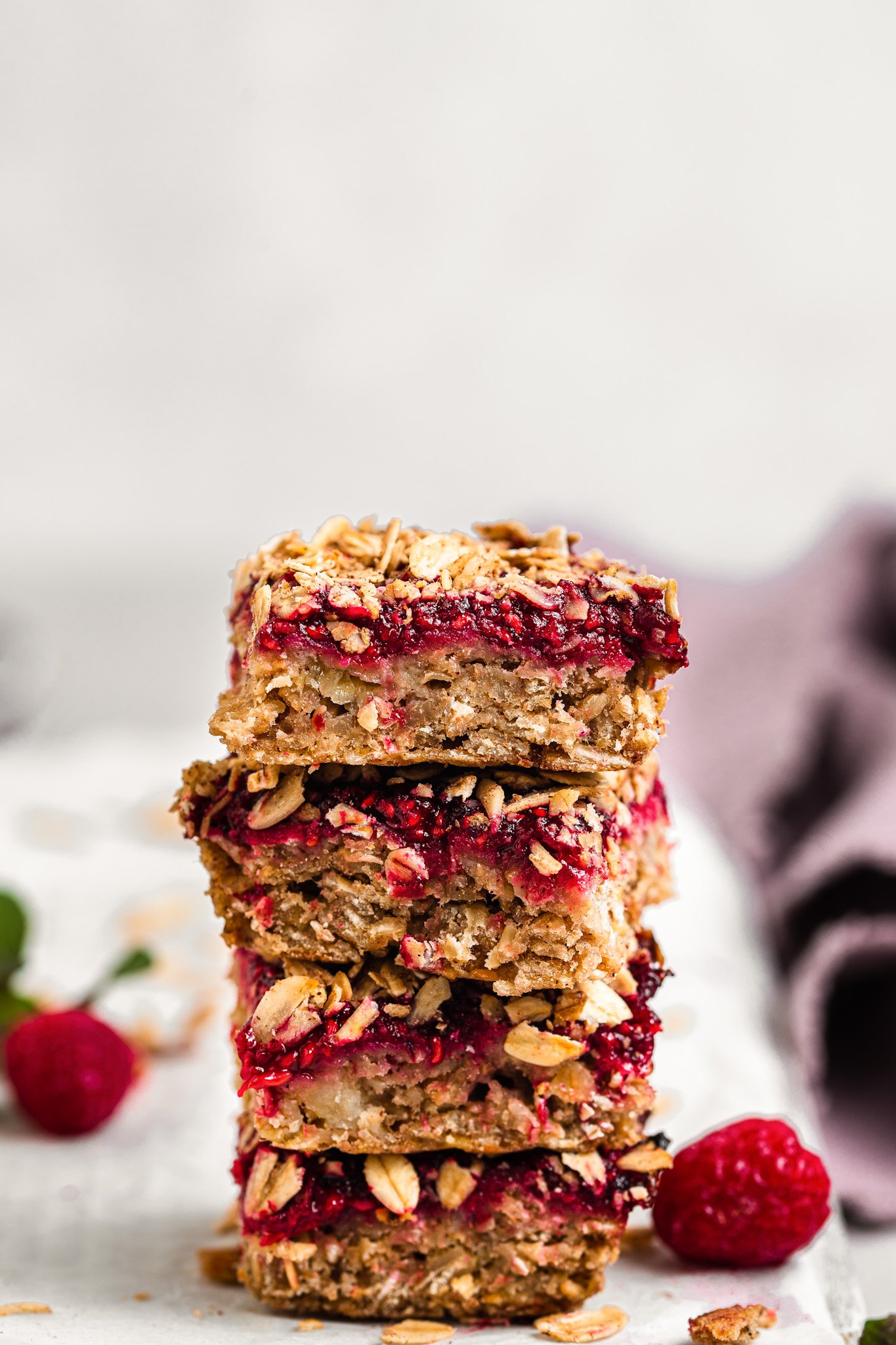 4 raspberry oat bars stacked one on top of the other.