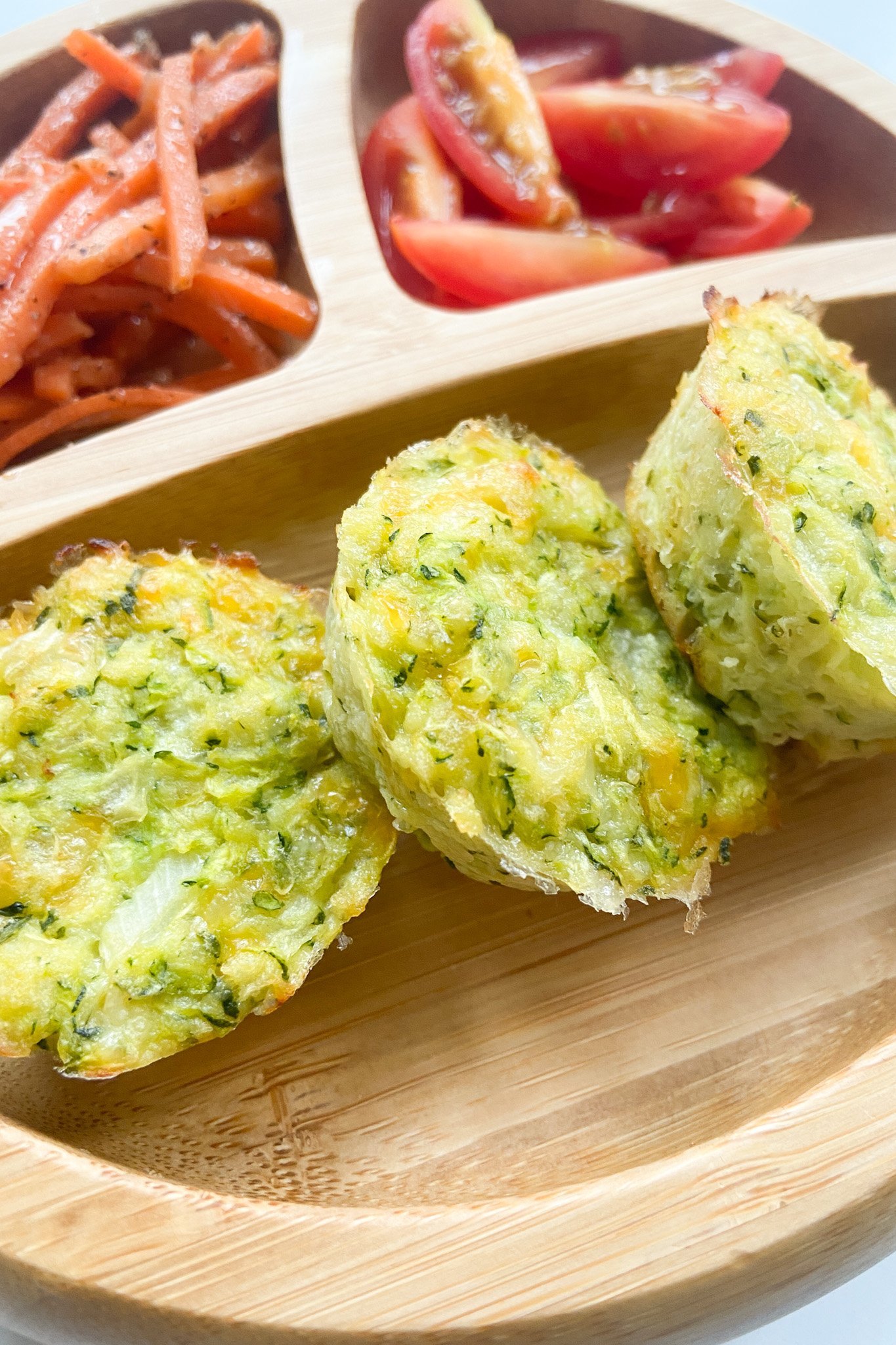Cheesy zucchini bites served with carrots and tomatoes