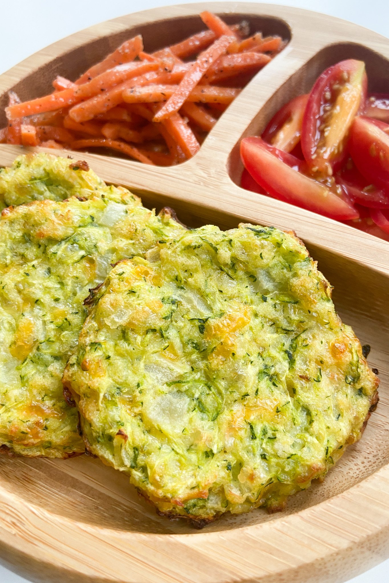Cheesy zucchini fritters served with carrots and tomatoes