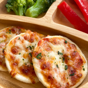 Homemade mini pizzas served with bell peppers and broccoli