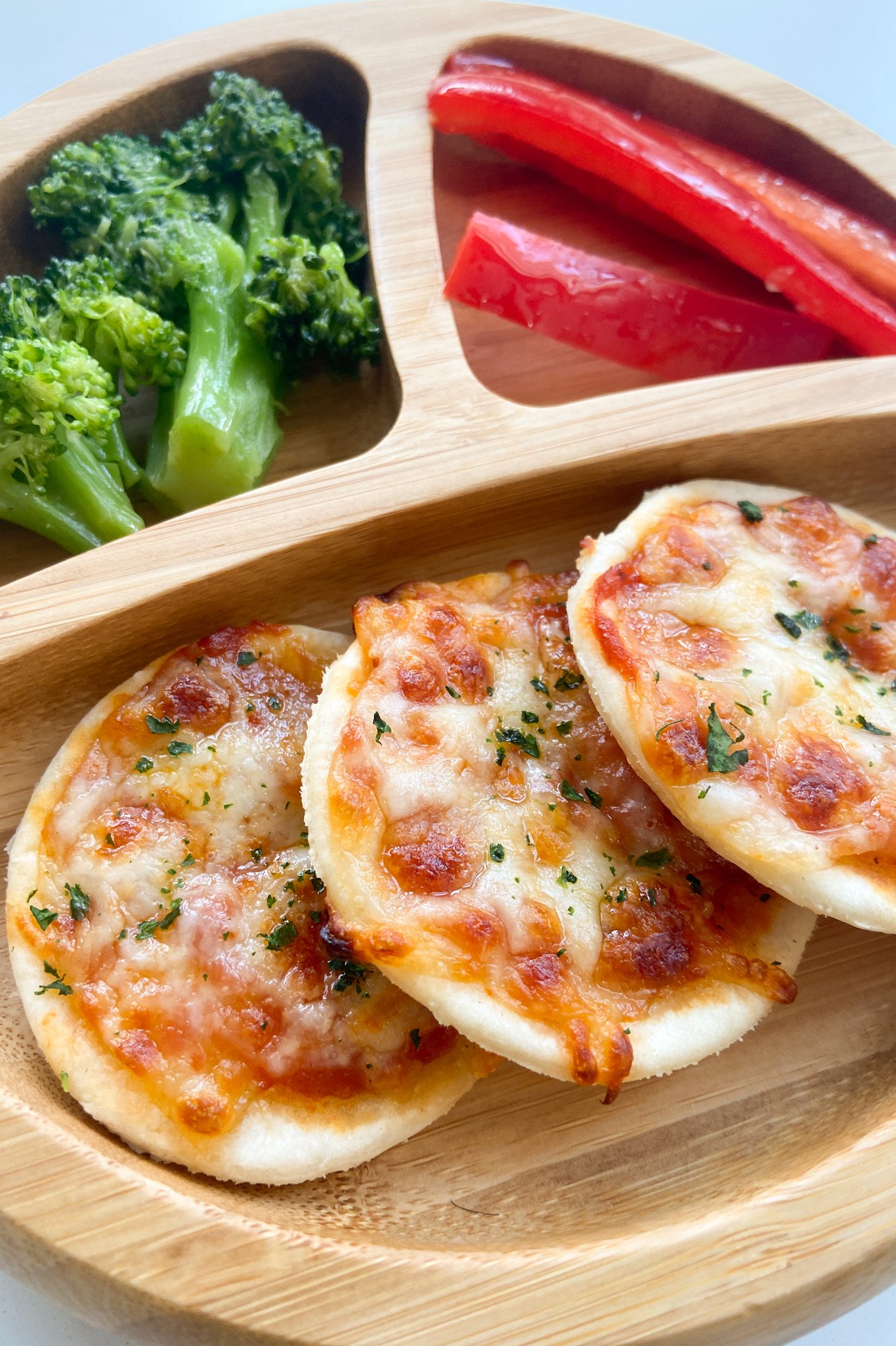 Homemade mini pizzas served with bell peppers and broccoli