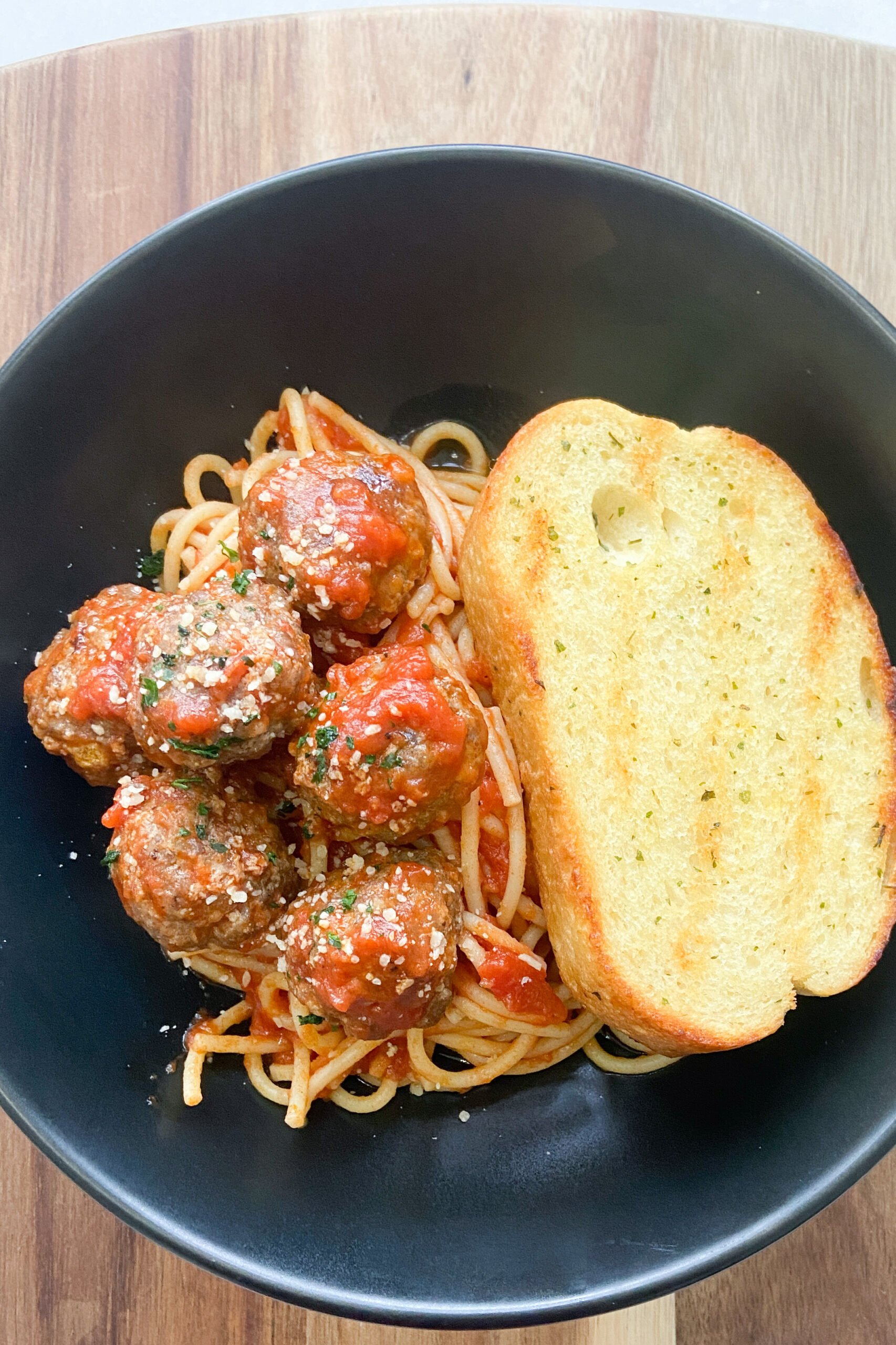 Meatballs served with spaghetti and garlic bread.