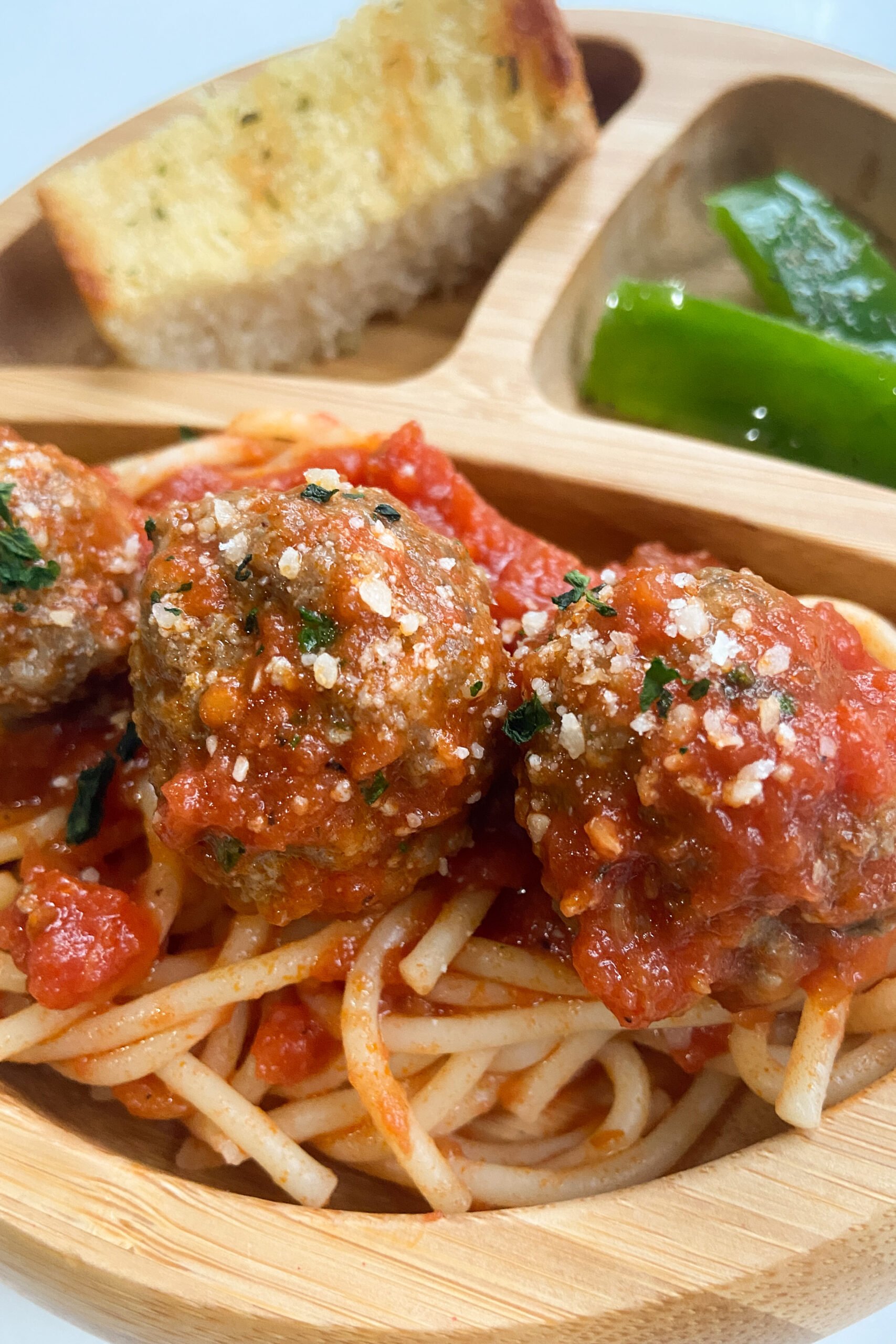 Meatballs served with spaghetti, garlic bread, and bell peppers.