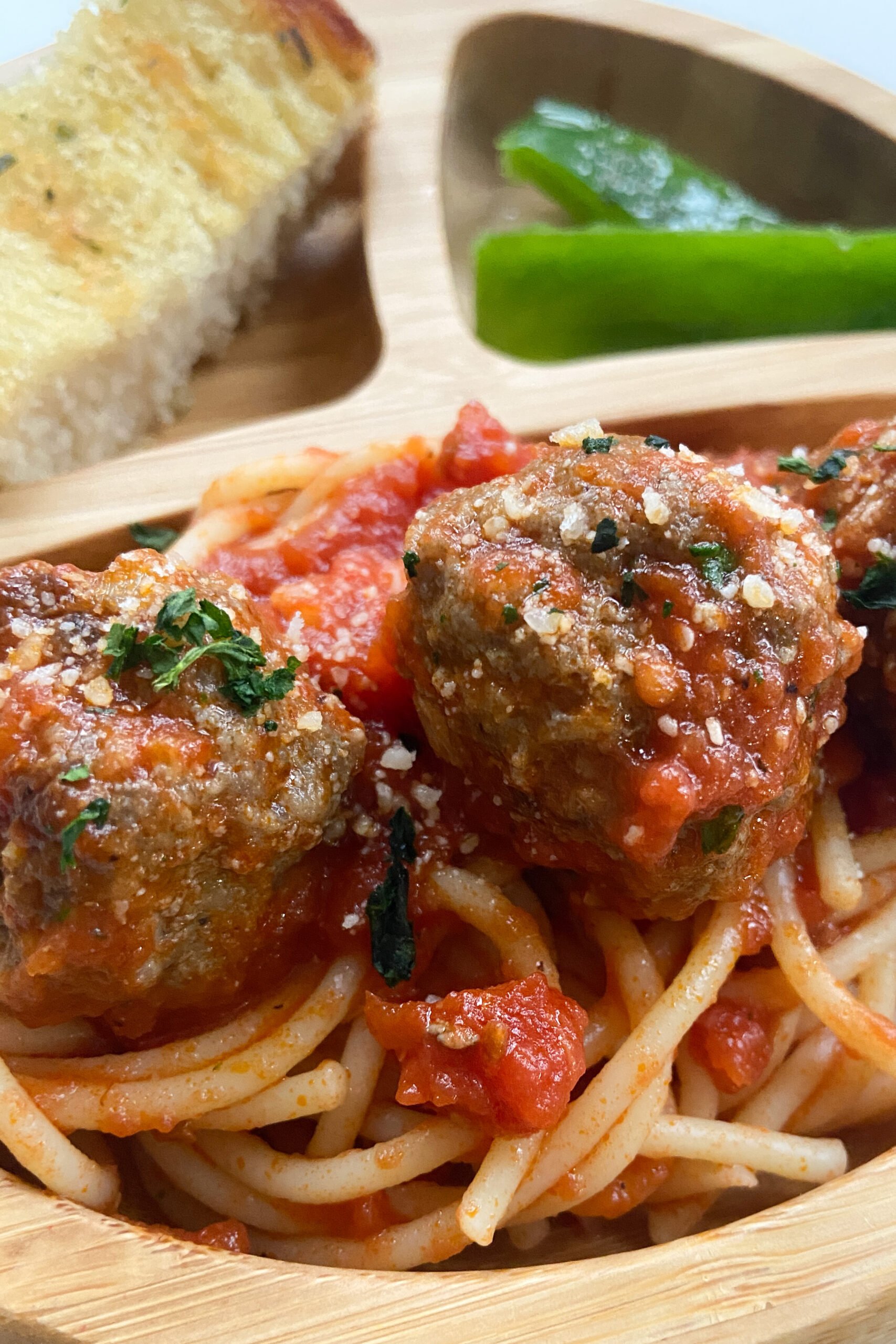 Meatballs served with spaghetti, garlic bread, and bell peppers.