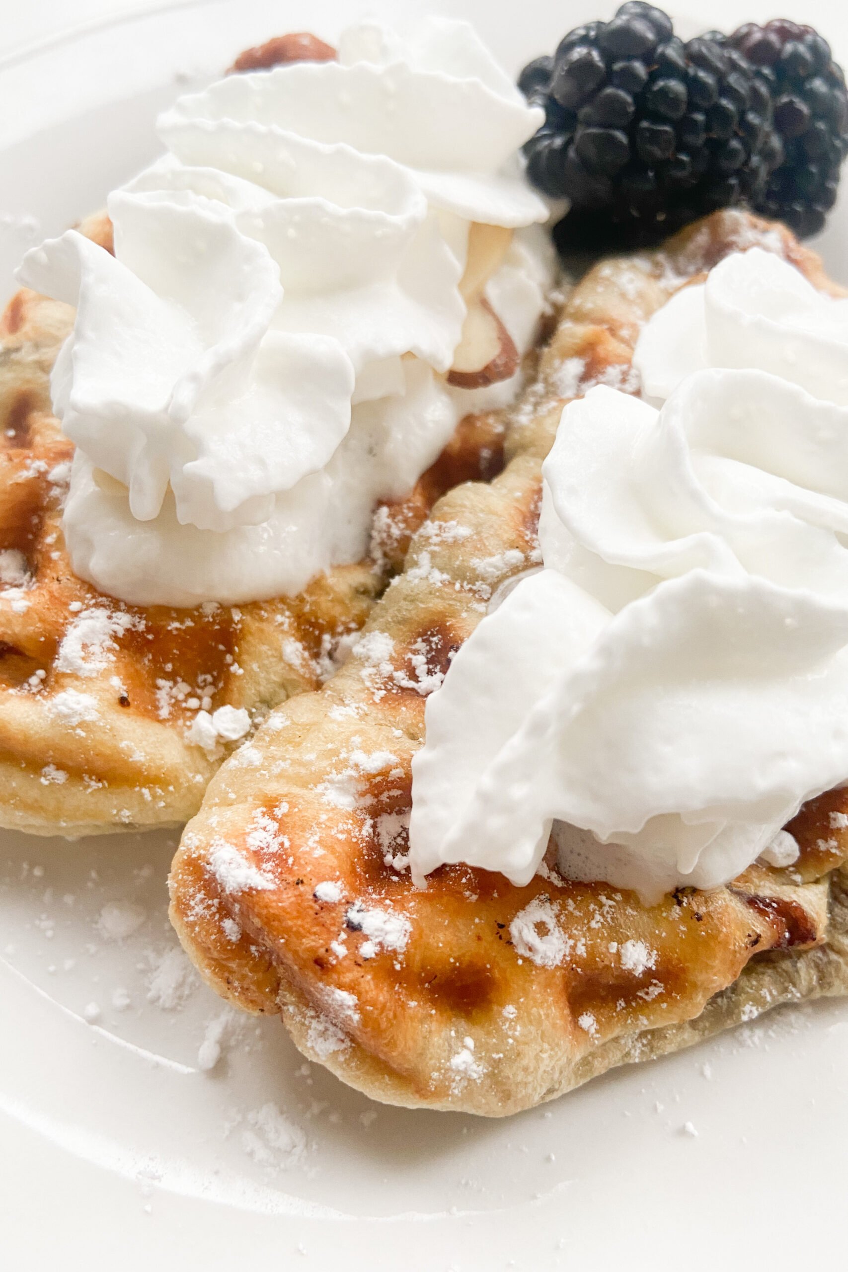 Croffles topped with whipped cream and powdered sugar.