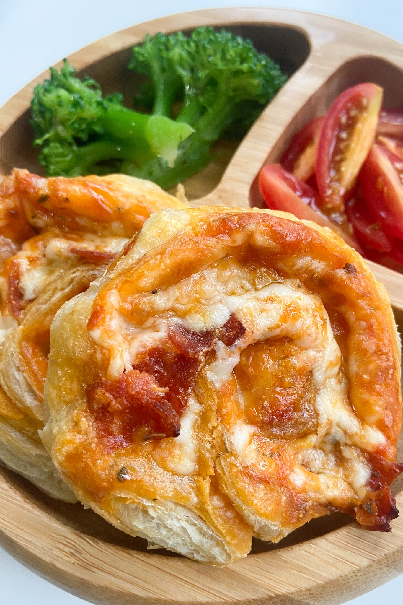 Pizza pinwheels served with broccoli and tomatoes