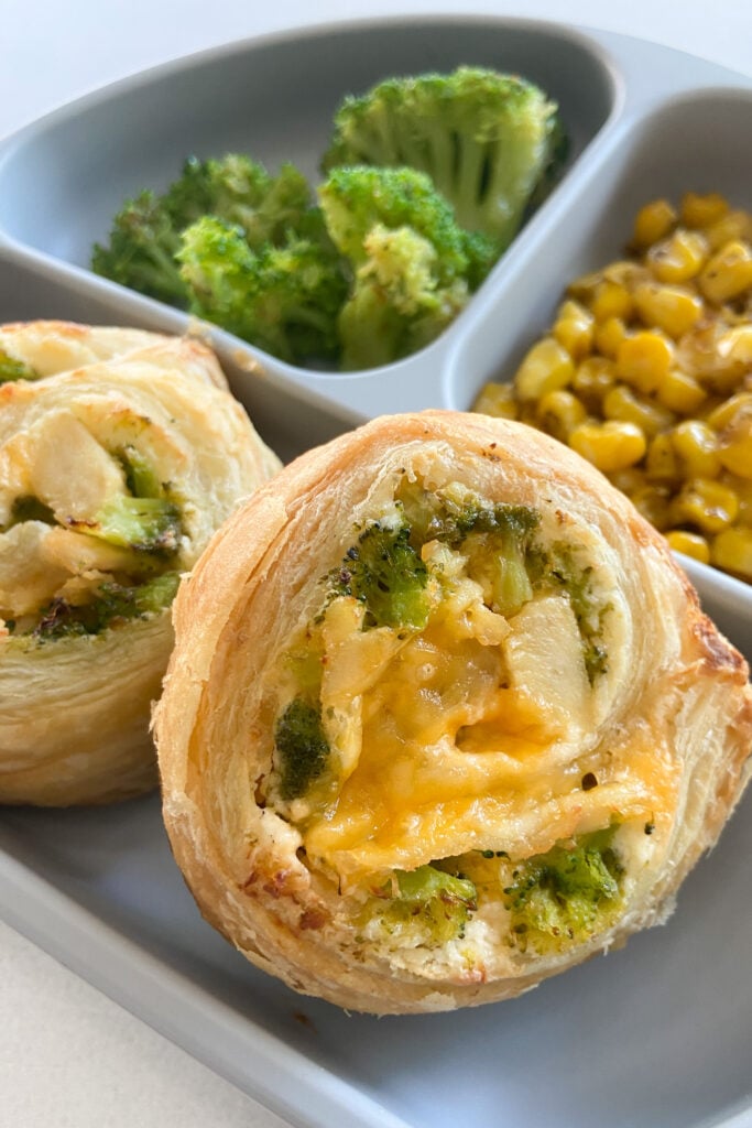 Broccoli and cheese pinwheels served with broccoli and roasted corn.
