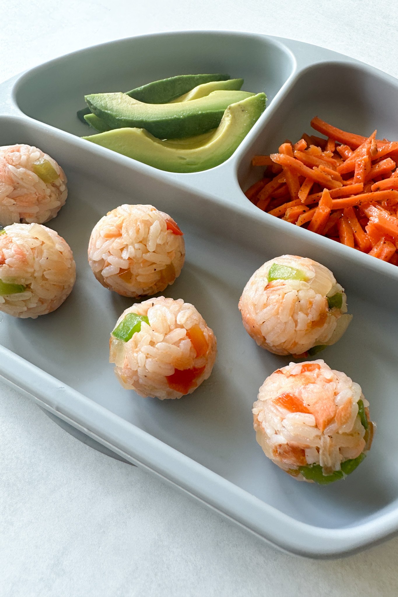 Salmon rice balls served with avocado and carrots.