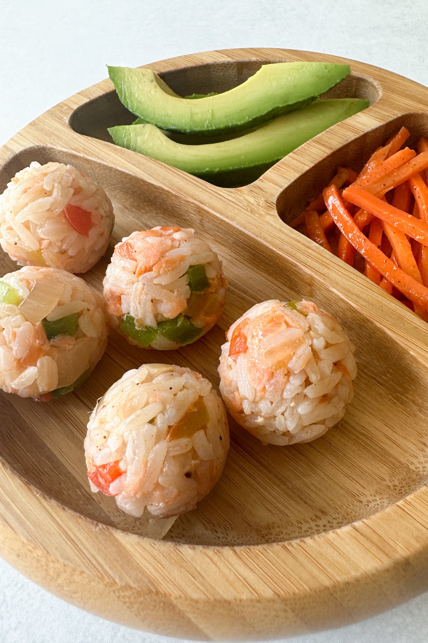 Salmon rice balls served with avocado and carrots.