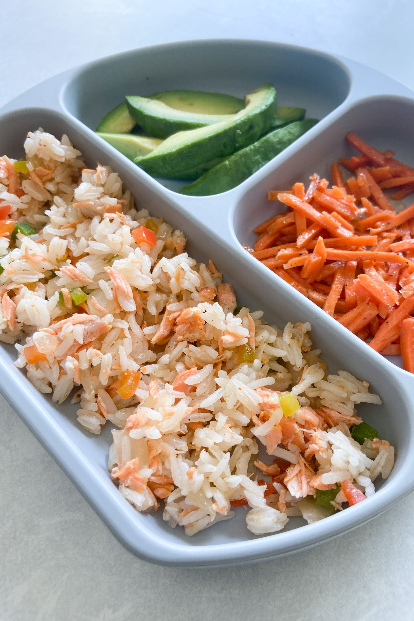 Salmon rice served with avocado and carrots.
