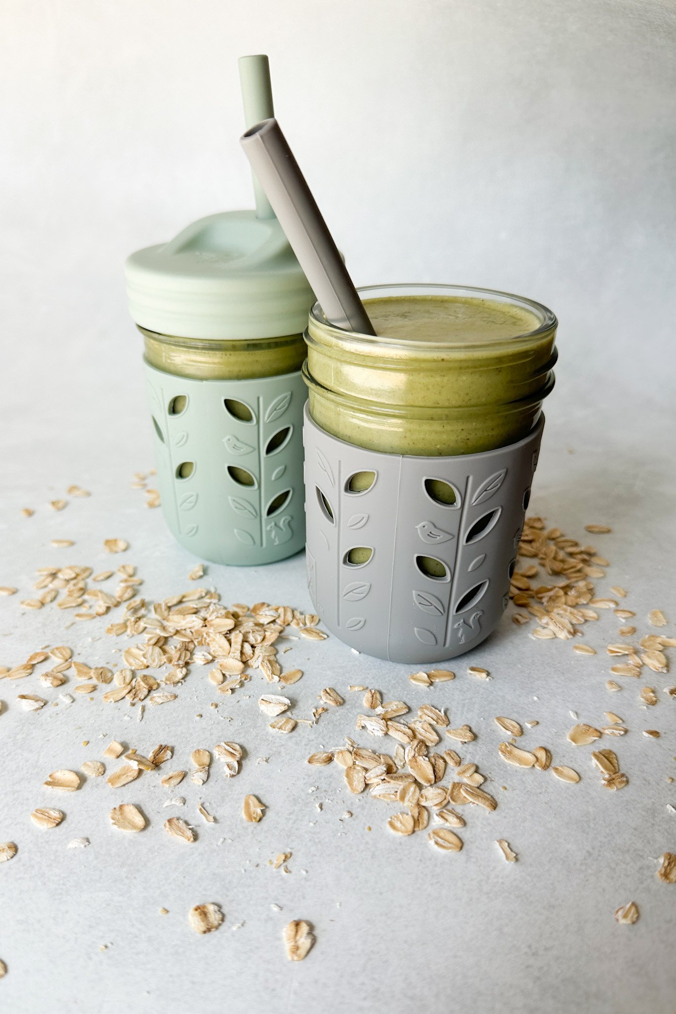 Spinach banana smoothies in toddler glass tumblers with silicone sleeves.