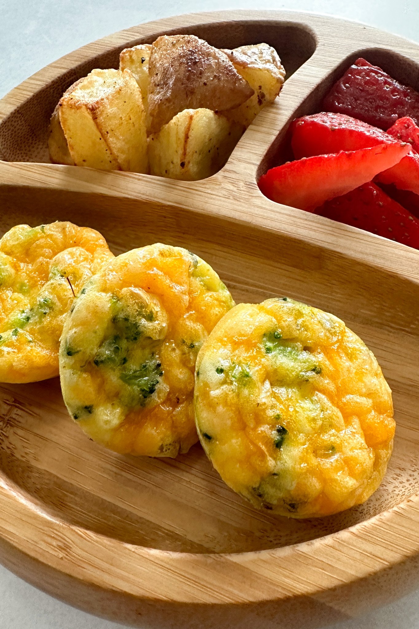 Broccoli egg bites served with fruits and potatoes.