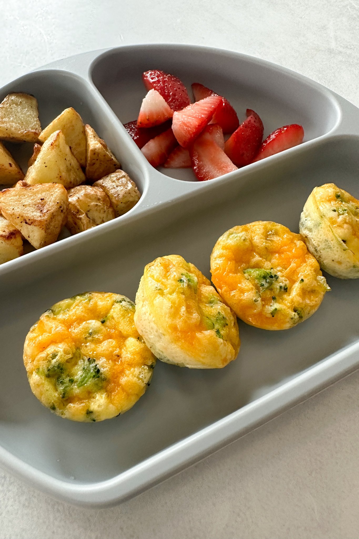 Broccoli egg bites served with fruits and potatoes.