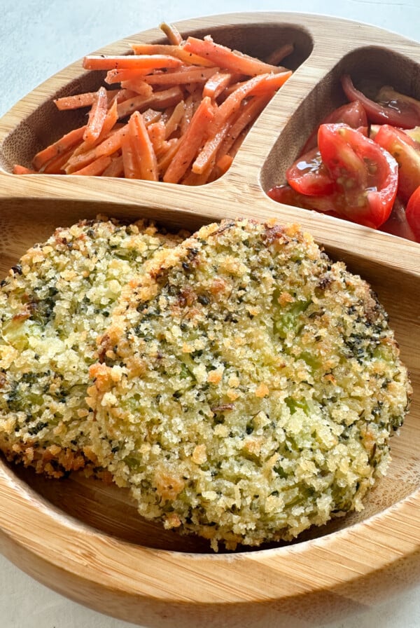 Broccoli patties served with carrots and tomatoes.