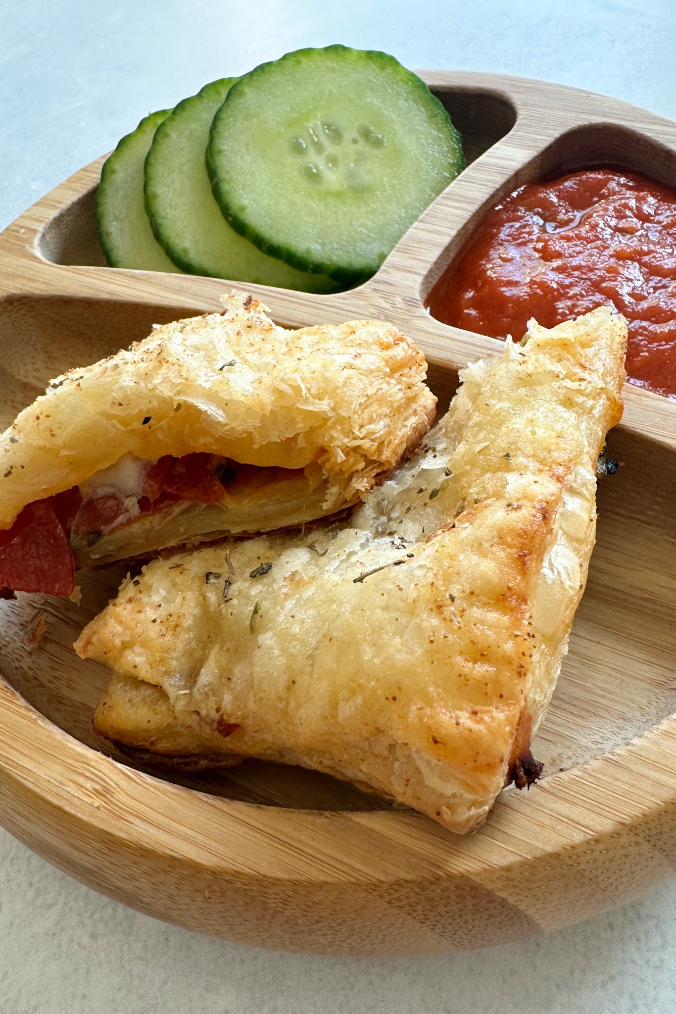 Puff pastry pizza pockets served with marinara sauce and cucumbers.