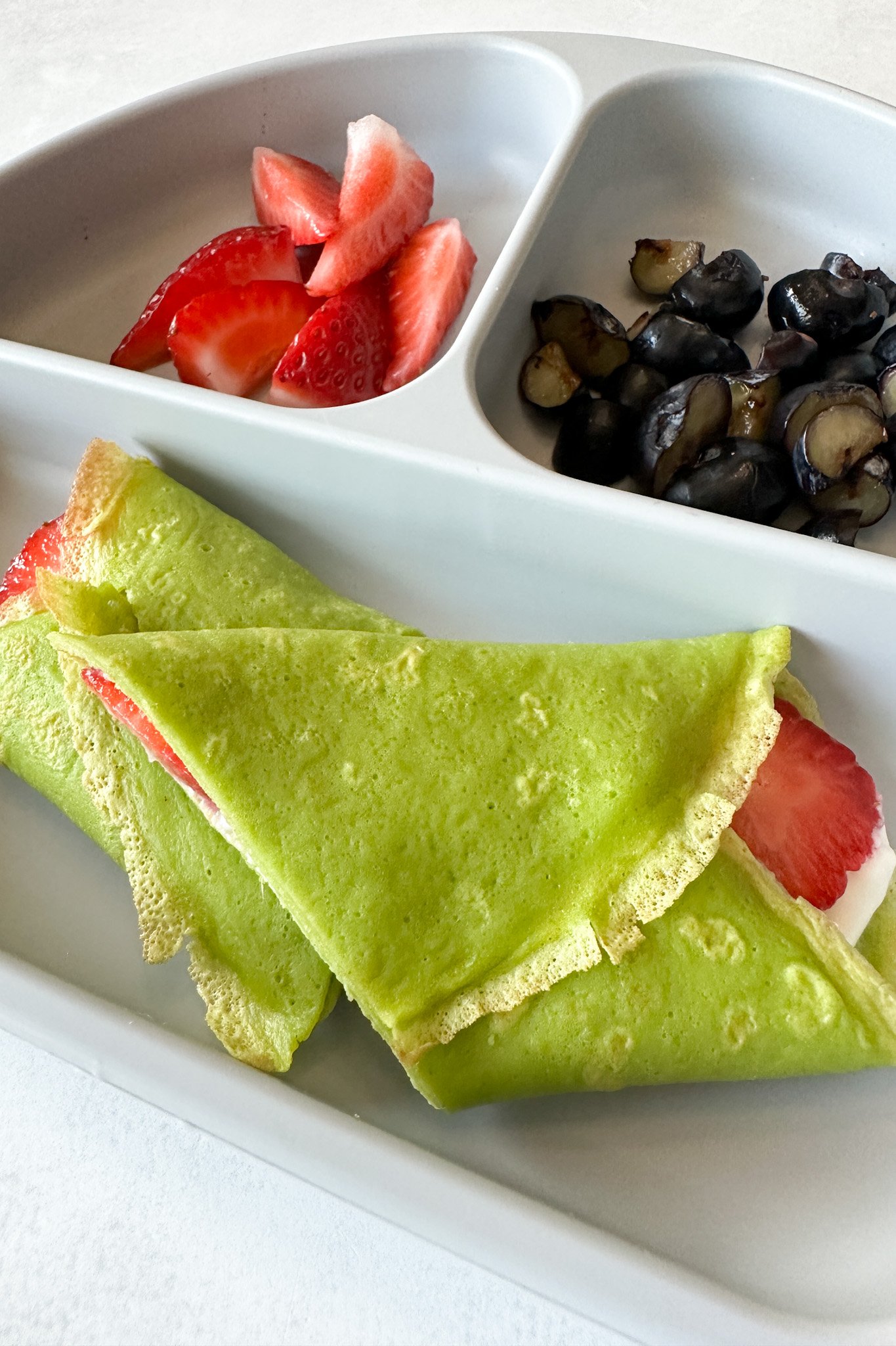 Spinach crepes filled with yogurt and strawberries.