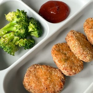 Veggie chicken nuggets served with broccoli and ketchup.