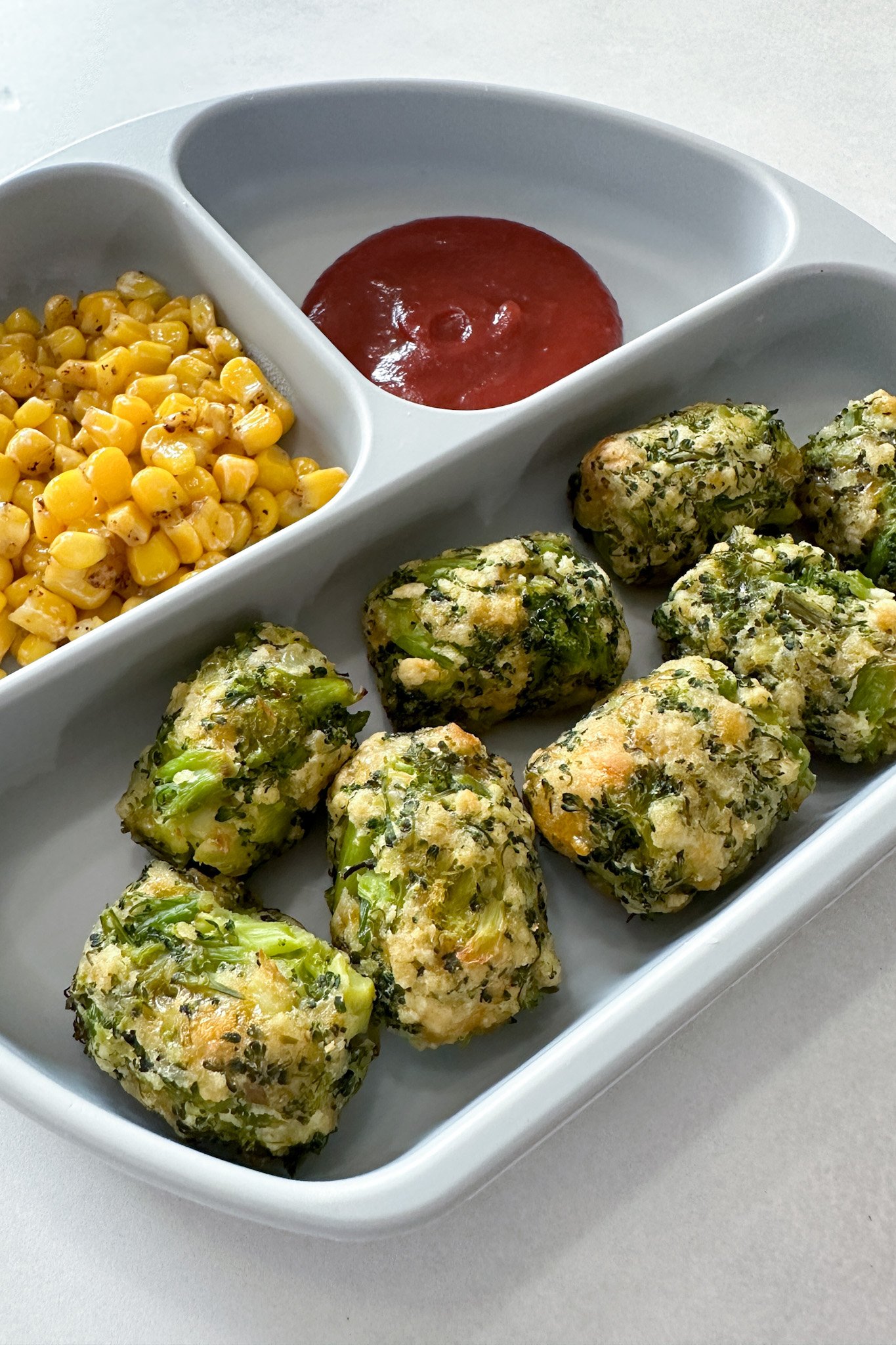 Broccoli tots served with corn and ketchup.