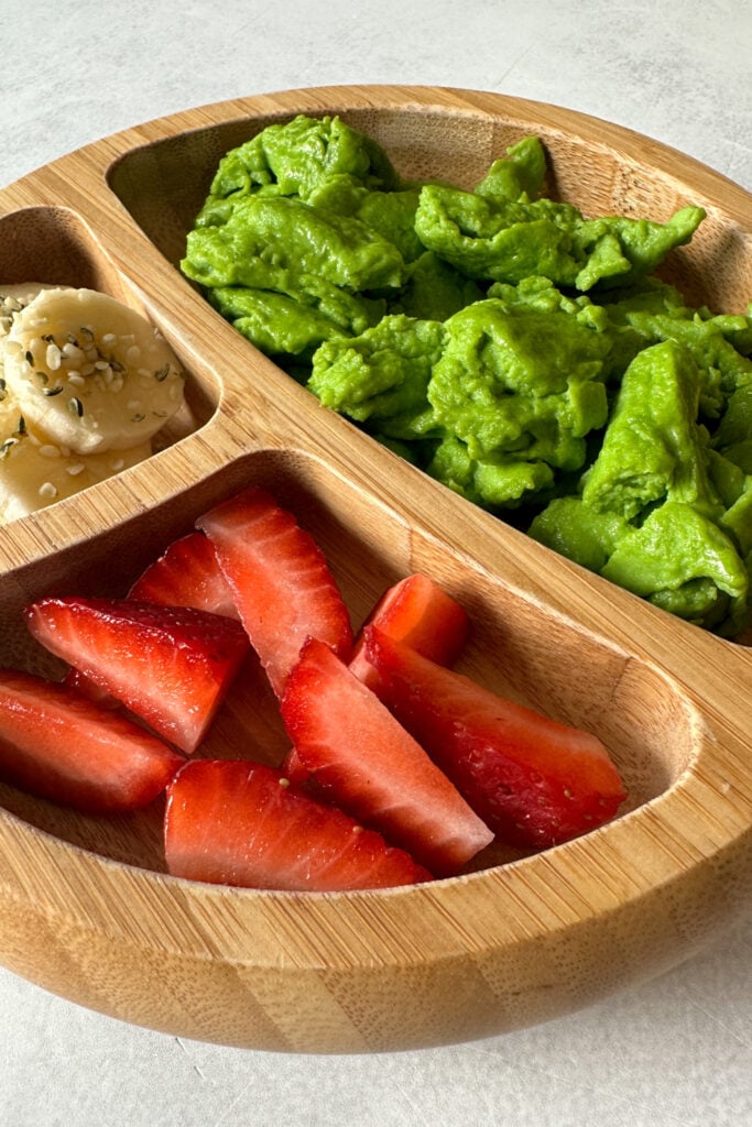 Spinach scrambled eggs served with bananas and strawberries.