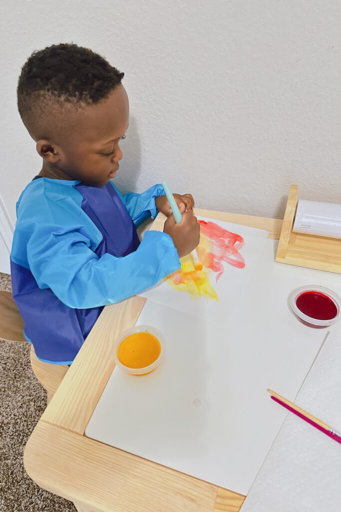 Toddler boy painting with Ikea Flisat table.