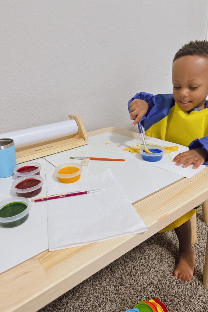 Toddler boy painting with Ikea Flisat table.