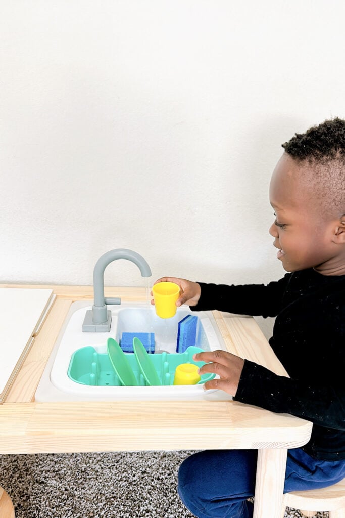 Toddler boy playing with play sink.