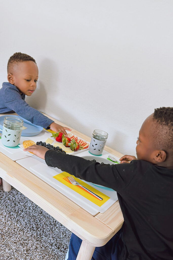 Toddler boys snacking on Ikea Flisat table.